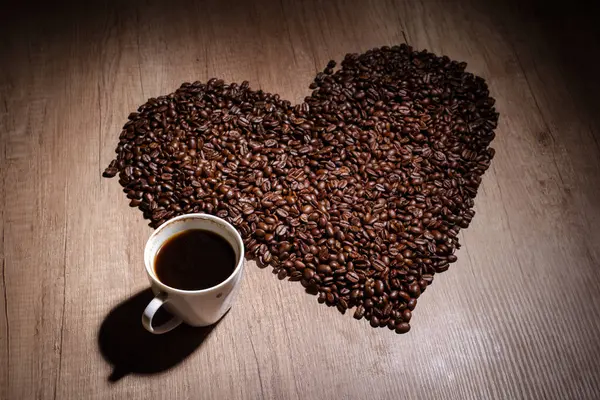 Cup of coffee with heart on wooden table