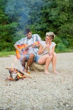 Genç çift sahilde kamp yaparken iyi vakit geçiriyor.