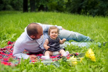 Küçük kız ve babası doğada piknik yapıyorlar.