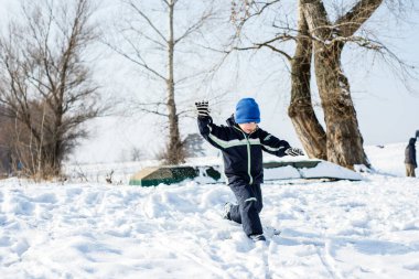 Çocuk karda eğleniyor, oynuyor.