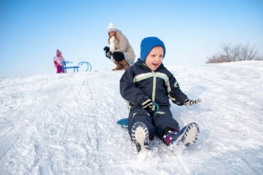 Oğlan karda eğleniyor. Büyük bir gülümsemeyle mutlu