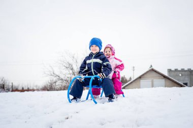 İki gülümseyen çocuk kızakta oturuyor..