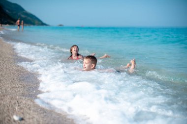 Kardeşler güzel, çakıllı plajda oynuyorlar.