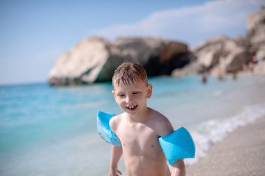 Bir çocuk güzel sahilde suyun kenarında yürüyor.