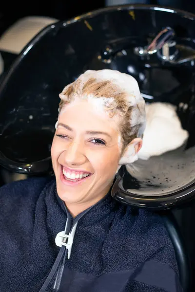 Kuafördeki sarışın kız, saçlarını yıkıyor.