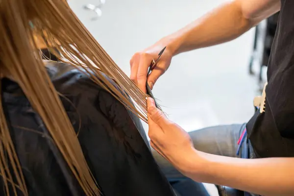 Sarışın saçlarını kesiyor.