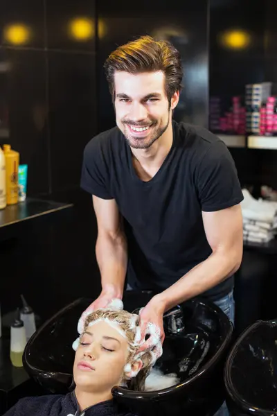 Kuaför genç sarışın kızların saçlarını yıkıyor.