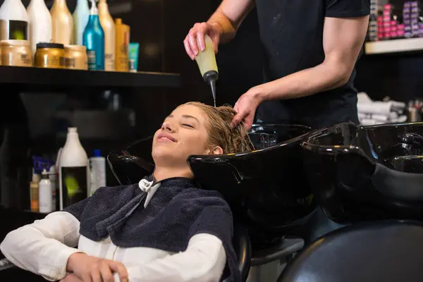 Kuaför kızların saçını sabunluyor.