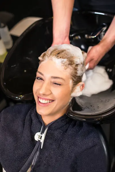 Kuaför çekici sarı saçları yıkıyor.