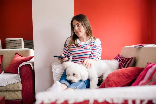 Girl and her pet on sofa watching TV in living room