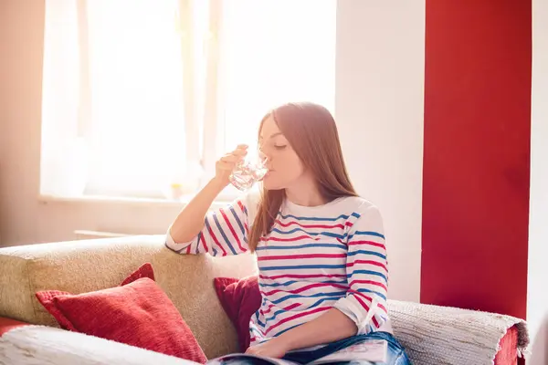 Woman is drinking water in living room