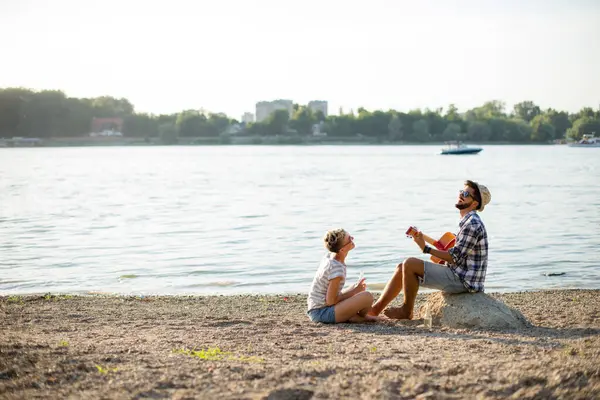 Sahildeki hippiler, gitar çalıp hayattan zevk alıyorlar.