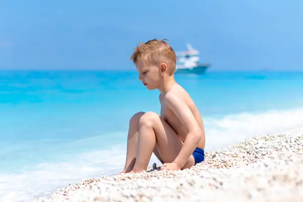 stock image A boy is playing on the beautiful, pebbly beach by the turquoise water