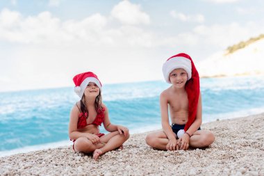 Noel Baba şapkalı küçük kız ve oğlan. Egzotik Noel kutlaması