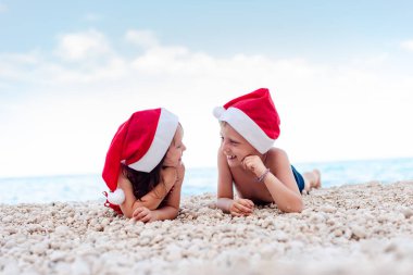 Birbirini kollayan Noel Baba şapkalı kardeşler. Modern Noel kutlaması