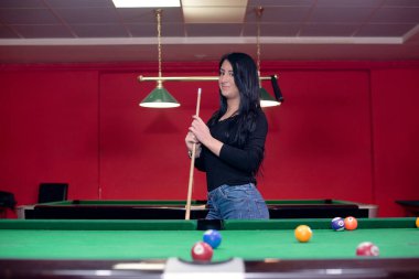 Esmer kız bilardo masasına bakıyor.