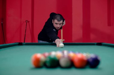 Çekici genç adam bilardo oynuyor.