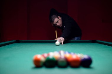Attractive young man is playing billiard clipart