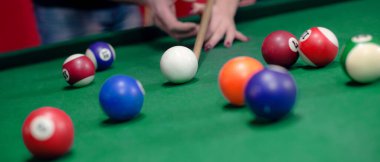 Adam kıza bilardo oynamayı öğretiyor.