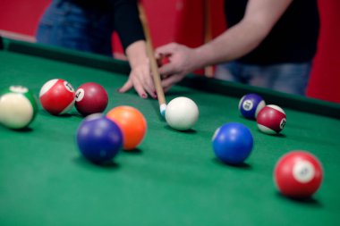 Adam kıza bilardo oynamayı öğretiyor.