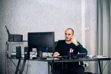 Küçük ofisinde bilgisayar başında çalışan ciddi bir iş adamı..