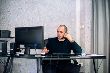 Kafkasyalı genç işadamı cep telefonuyla iş görüşmesi yapıyor, ofisinde oturuyor..