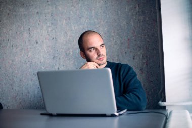 İşadamı düşüncelere dalmış, ofiste oturuyor ve başka tarafa bakıyor..