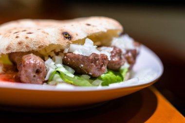 Close up of Serbian fast food, grilled pork meat with lettuce and onion in bread. clipart