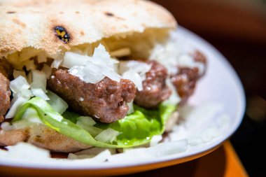 Hamburger, marul ve soğanı tabakta yakın..