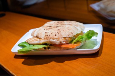 Tavuk göğsü, marul ve domatesli hamburger, yemek için servis ediliyor..