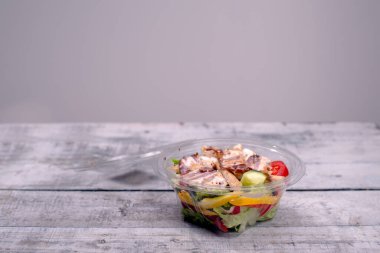 Masada bir kase taze salata, gri arka plan.