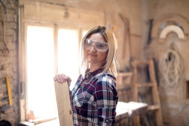 Genç ve çekici sarışın kadın marangoz atölyesinde çalışıyor.