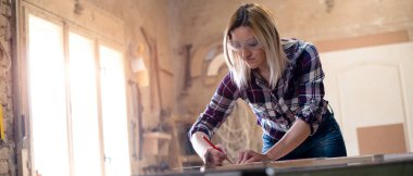 Genç ve çekici sarışın kadın marangoz atölyesinde çalışıyor.