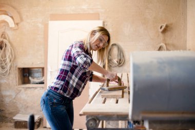 Genç ve çekici sarışın kadın marangoz atölyesinde çalışıyor.