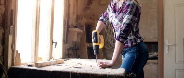 Genç ve çekici sarışın kadın marangoz atölyesinde çalışıyor.