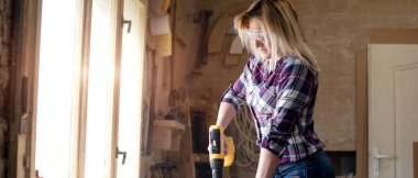 Genç ve çekici sarışın kadın marangoz atölyesinde çalışıyor.