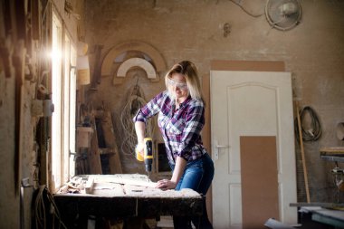 Genç ve çekici sarışın kadın marangoz atölyesinde çalışıyor.