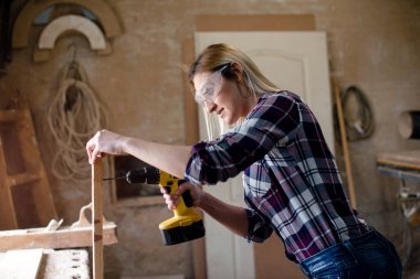 Genç ve çekici sarışın kadın marangoz atölyesinde çalışıyor.