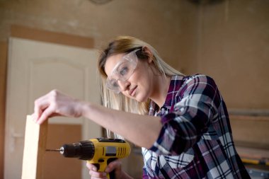 Genç ve çekici sarışın kadın marangoz atölyesinde çalışıyor.