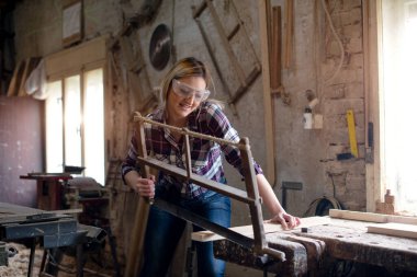 Genç ve çekici sarışın kadın marangoz atölyesinde çalışıyor.