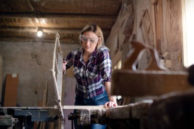 Genç ve çekici sarışın kadın marangoz atölyesinde çalışıyor.