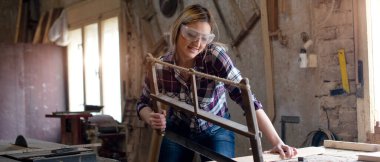 Genç ve çekici sarışın kadın marangoz atölyesinde çalışıyor.