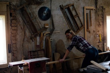 Genç ve çekici sarışın kadın marangoz atölyesinde çalışıyor.