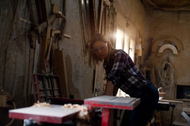 Genç ve çekici sarışın kadın marangoz atölyesinde çalışıyor.