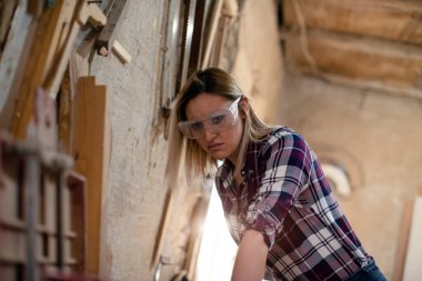 Genç ve çekici sarışın kadın marangoz atölyesinde çalışıyor.