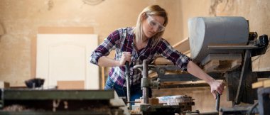 Genç ve çekici sarışın kadın marangoz atölyesinde çalışıyor.