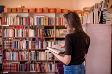 Kütüphanede dikiz aynasından kitap okuyan bir kadın.