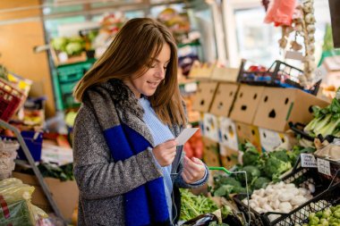 Marketteki kadın alışveriş listesini kontrol ediyor..