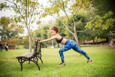 Spor eğitiminin sonuna doğru esneme hareketleri yapan genç bir kadın..