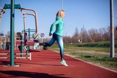 Dışarıda spor aletleri üzerinde egzersiz yapan genç bir kadın..